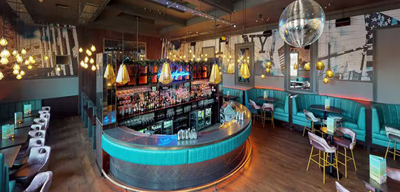 Circular teal bar counter beneath a disco ball and gold pendant lights