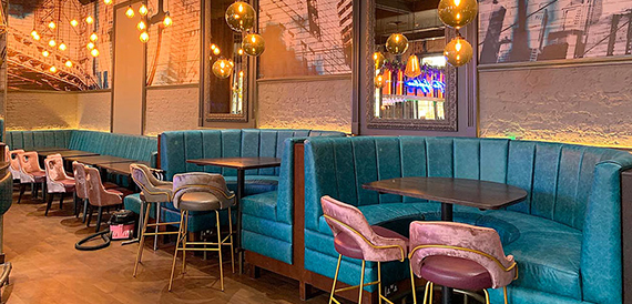 Teal booth seating beneath gold pendant lights and framed skyline prints