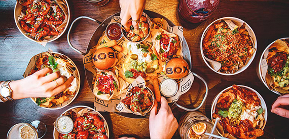 Overhead view of shared platters, burgers and nachos on a wooden table