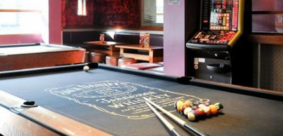 Close-up of a pool table with balls racked and cues ready