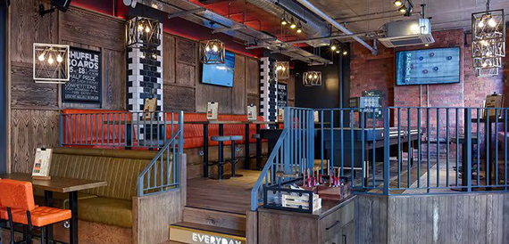 Split-level lounge with exposed brick, orange booths and a staircase