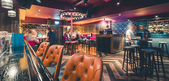 Orange leather booths beneath a glowing circular pink light