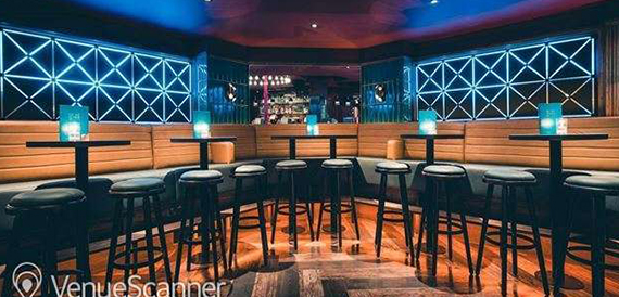Bar counter with blue tiled backdrop and rows of high stools