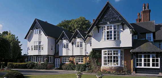 Exterior of the white and black timber-framed country house hotel with lawns.