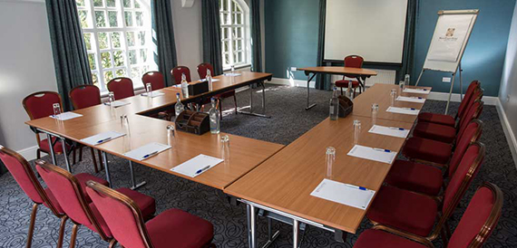 Meeting room set u-shape with red chairs and a projector screen.