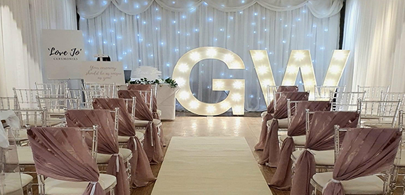 Wedding ceremony room with light-up GW letters and a fairy-light backdrop.
