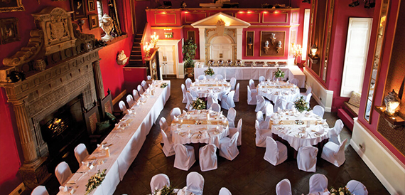 Red drawing room set for a wedding breakfast with a large fireplace and chair covers