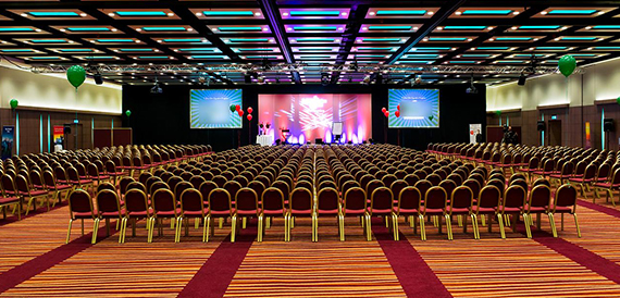 Large ballroom set theatre-style with hundreds of chairs facing a lit stage