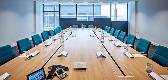 Boardroom with a long table, teal chairs and a conference phone.
