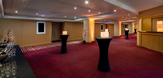 Pre-function corridor with illuminated cocktail tables and a canape station