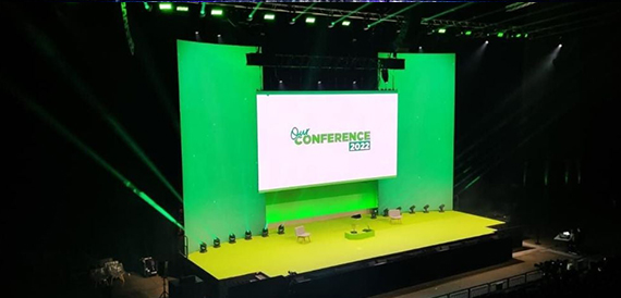 Empty stage with a large screen and green lighting for a conference.