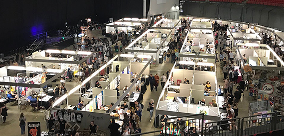 Aerial view of a busy market-style exhibition with rows of trader stalls.