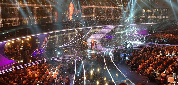 Stage performance with confetti falling under dramatic lighting effects.