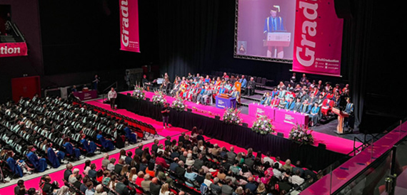 Graduation ceremony in the auditorium with pink Graduation banners on stage