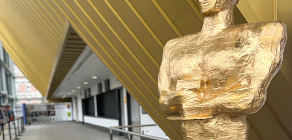 Close-up of a gold statue in a corridor beneath gold ceiling panels