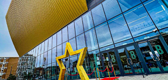 Venue exterior with a gold curved roof, glass facade and star sculpture
