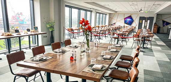 Dining room with wood tables, red flowers and floor-to-ceiling windows