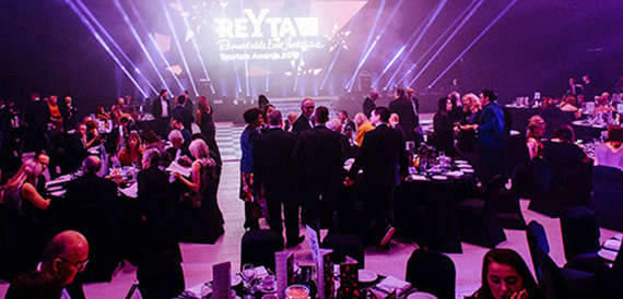 Awards event with guests mingling beneath purple stage lighting and a ReYTA banner