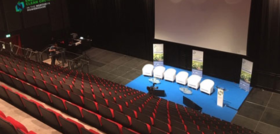 Auditorium with red seating set up for a panel discussion on stage