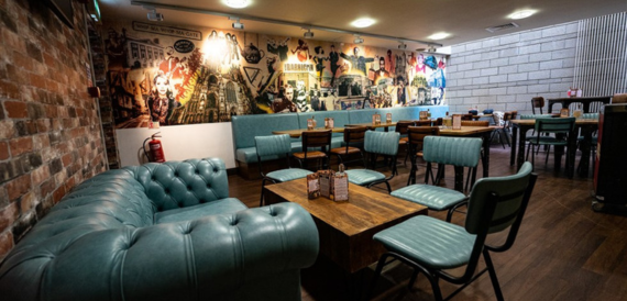 Bar lounge with teal leather booths beside a graffiti-style mural wall
