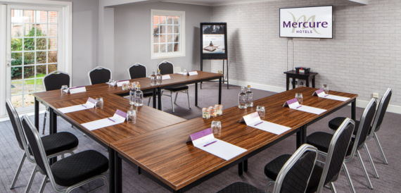 Meeting room set u-shape with black chairs facing a Mercure screen.
