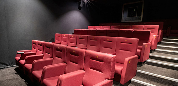 Screening room with red tip-up seats and gold row numbers