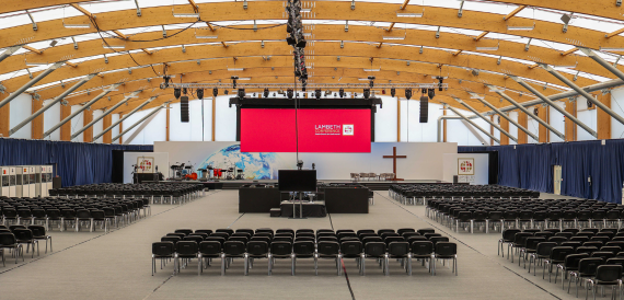 Large marquee-style hall set with rows of chairs facing a big screen
