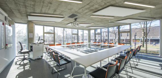 Boardroom-style meeting room with a U-shaped table and orange-accented chairs