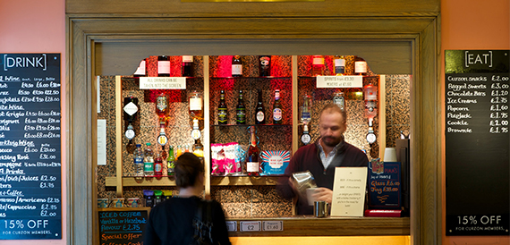 Concession counter with drink and snack menus and a member of staff serving