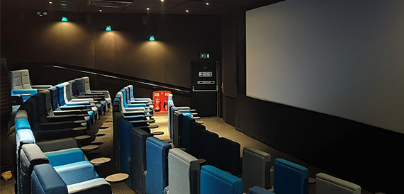Screening room with blue-grey seats facing a blank projection screen