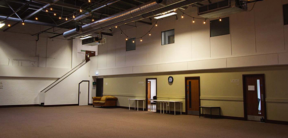 Empty hall with festoon lighting, a staircase and wooden flooring