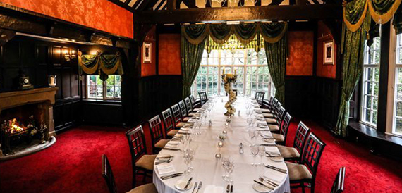 Private dining room with a long table, red carpet and an open fireplace.