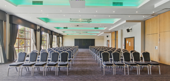 Conference room set theatre-style with grey chairs beneath green mood lighting
