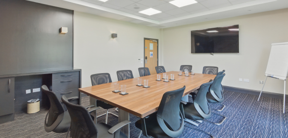 Long boardroom table with black chairs set for a meeting