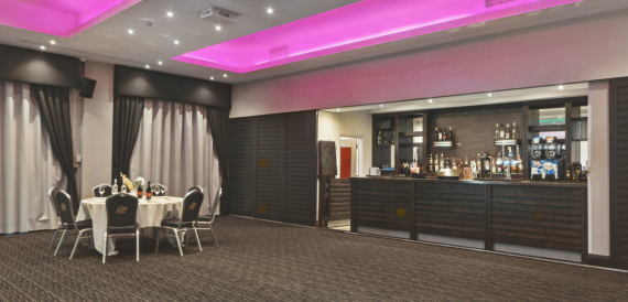 Bar area with dark wood counter and pink ceiling lighting