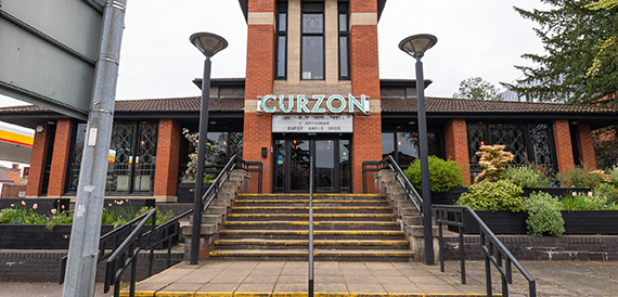 Curzon's red-brick exterior with entrance steps and lamp posts either side