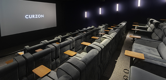 Cinema screening room viewed from the side with rows of grey seats