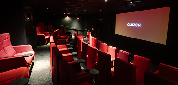 Screening room with curved red velvet seats facing an illuminated screen