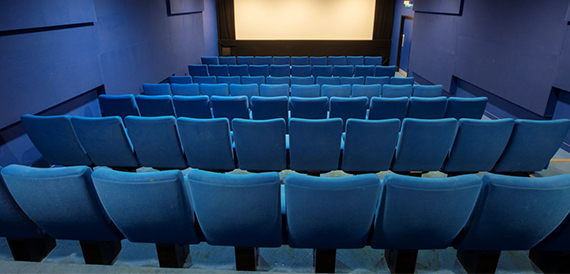 Cinema auditorium with blue seats facing a large screen