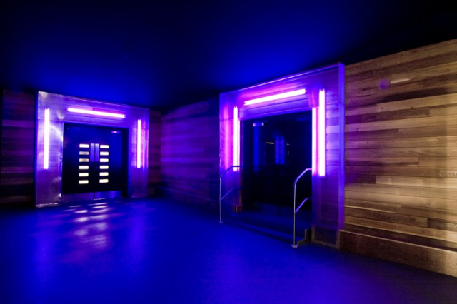 Neon-lit corridor with pink and purple lighting leading to dark doorways