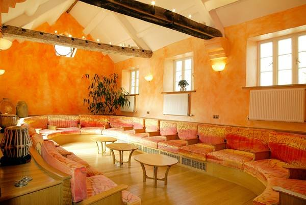 Curved lounge seating in a warm orange room with patterned cushions and a domed roof