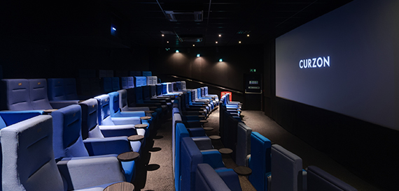 Screening room with blue seats and small side tables facing the screen