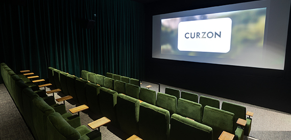 Screening room with green seats and a glowing Curzon screen