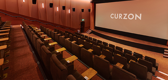 Cinema auditorium with brown seats facing an illuminated screen