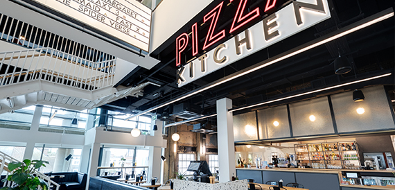 Pizza Kitchen neon sign above a bar counter and staircase