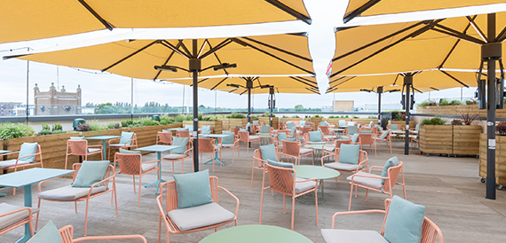 Rooftop terrace with yellow umbrellas, pink chairs and round tables
