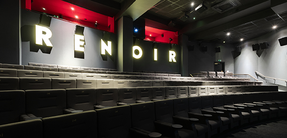 Screening room with red neon signage and rows of leather seats