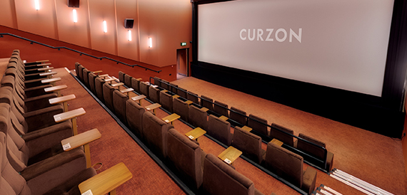 Cinema auditorium with brown tip-up seats and wood-panelled walls