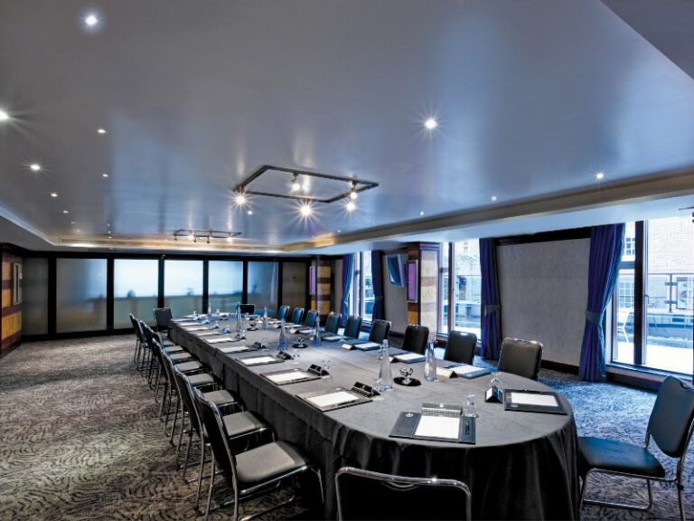 Meeting room set U-shaped with black chairs behind glass partition walls