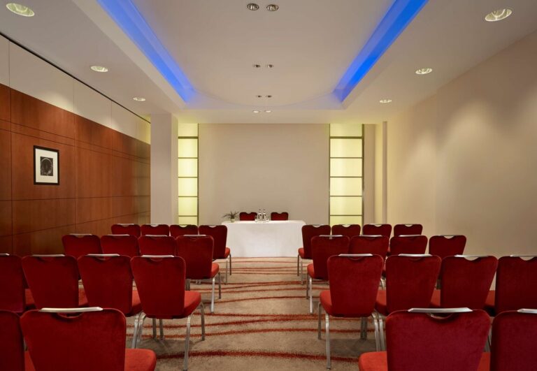 Albert 1 meeting room set theatre-style with rows of red velvet chairs facing a skirted table.